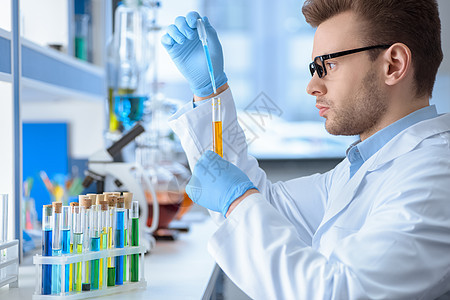 实验室化学家实验的侧面视图在实验室进行化学品眼镜职业工作服男人乳胶成人防护试剂科学家图片