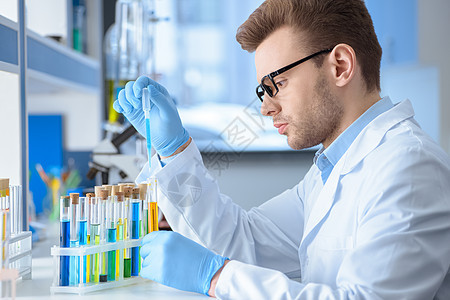 实验室化学家实验的侧面视图在实验室进行科学化学品化学手套防护成人工作服试剂烧瓶男人图片