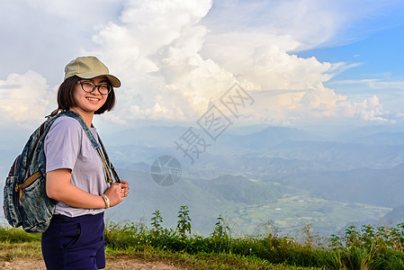 在山上登山的年轻女孩徒步旅行者旅行女士女性眼镜天空顶峰场景闲暇森林风景图片