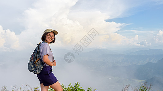 在山上登山的年轻女孩徒步旅行者景点眼镜森林背包场景远足青少年女性公园顶峰图片