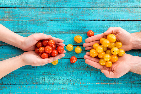 手握樱桃图案蔬菜水平两个人蓝色黄色西红柿桌子食物高架视图图片