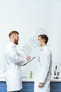 讨论实验室实验结果的白大衣中科学家的侧面观点口罩合作白大褂成人安全风镜科学家们化学职业化学品图片