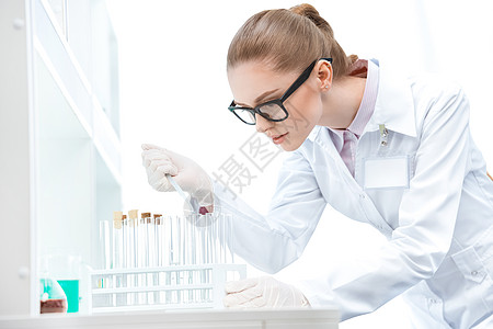 年轻 集中的女性科学家 在眼镜中工作 使用测试管和管子图片