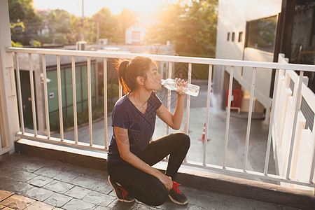 运动妇女放松时间和饮用水休闲身体摄影冷饮训练生活方式阳光城市人体耳机图片