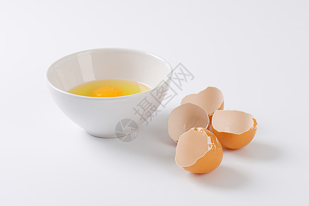 碗里的鸡蛋碎裂蛋黄蛋白棕色食物蛋壳盘子背景图片
