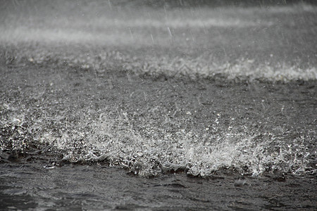 地面大雨雨量水坑灰色飞溅波纹天气雨滴淋浴水滴背景图片