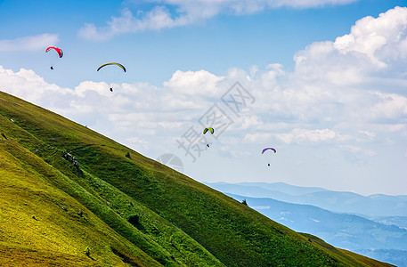 在山上滑雪 飞得极远天空运动金库山坡季节地球天蓝色爬坡活动降落伞图片