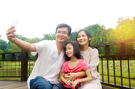 幸福的亚洲家庭男人自拍公园手机女孩照片夫妻电话生活树木图片