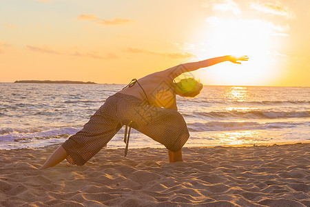 日落时在海边做瑜伽的女人女孩女士身体运动平衡自由训练海滩天空阴影图片