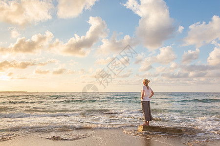 自由快乐女人享受桑迪海滩的日落日出黄金岩石时段海浪天空女孩天堂金发阳光图片