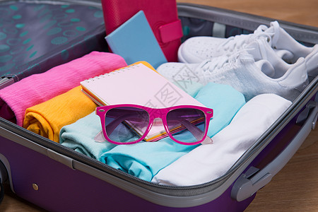旅行和休假概念 开放旅行者带衣物的包袋桌子卡片配件衣服护照手提箱旅游游客相机行李图片