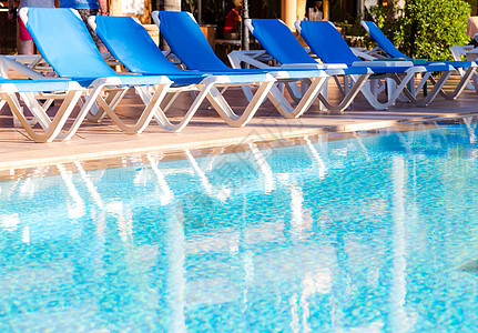 笼子前后在游泳池周围安排的蓝色甲板椅子游泳棕榈海洋学期时间旅游海滩天堂季节年假图片