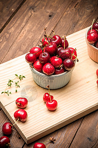 陶瓷碗中的红熟樱桃蓝色桌布饮食果汁厨房制品木头宏观花园甜点图片