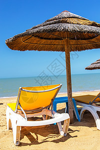 热带海滩上的海滩雨伞和甲板椅椅子休息室躺椅风景假期晴天阳伞天堂海岸遮阳棚图片