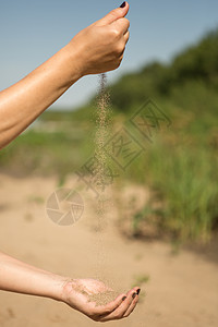 撒沙在女人的手中奔跑损失水平摄影财富时间跑步滴漏细流粮食手指图片