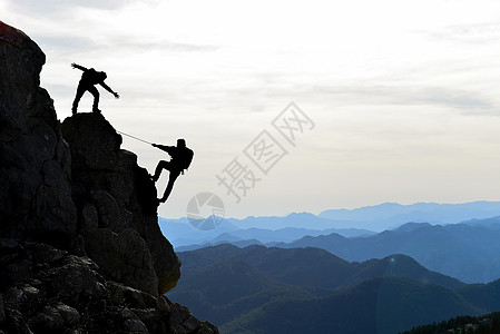 帮助 支持和兴趣的攀爬者绳索挑战性力量悬崖攀岩自由冒险团队朋友高峰期图片