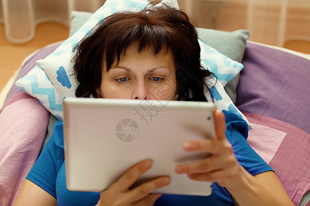 中年妇女用平板板在床上休息卧室技术互联网电脑电子书阅读白色幸福说谎购物图片
