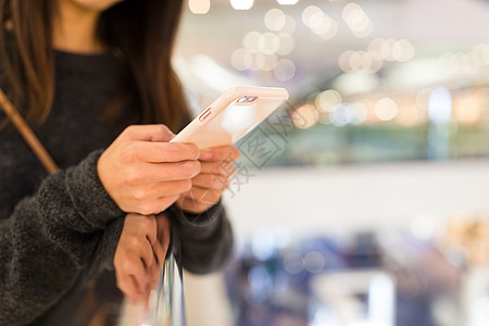 女性使用移动电话的情况短信女孩店铺背景购物中心金子桌子手机互联网木头图片