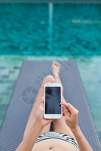 妇女使用带有游泳池的移动电话的情况图片