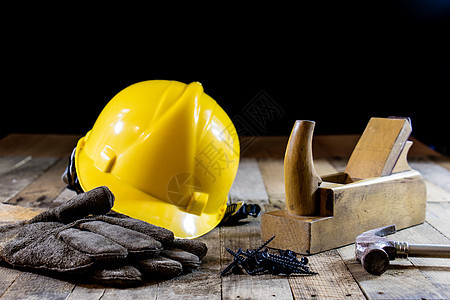 黄头盔和木匠工具 木匠和旧木板石工背心塑料红色危险锤子安全帽工作工人工业图片