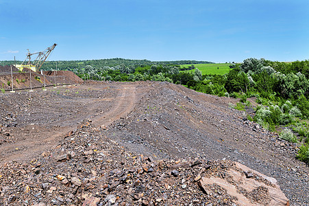 采石场挖掘土方工程中的挖掘机石头材料金属河道生态机器植被环境石英岩尾矿背景图片
