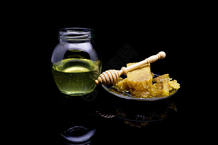 黑色背景中隔离的玻璃板上带有蜂窝的蜂蜜产品糖浆金子健康液体药品厨房甜点蜂蜡木头图片