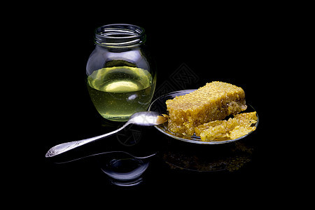 黑色背景中隔离的玻璃板上带有蜂窝的蜂蜜液体食物勺子玻璃早餐甜点木头药品厨房产品图片
