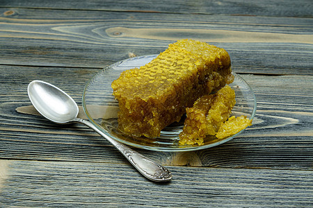 蜂蜜与蜂窝蜂蜜 在旧木制桌子上的玻璃盘子上蜜蜂甜点勺子木头食物营养厨房液体产品早餐图片