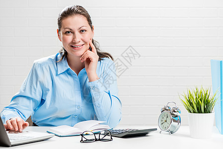 穿着办公室服装的女孩在脱衣的一张桌子上的笔记本电脑上工作图片