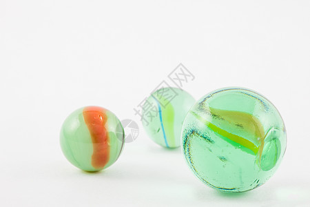 在白色背景上孤立的玻璃大理石球绿色童年团体气泡玩具游戏孩子橙子宏观弹珠图片
