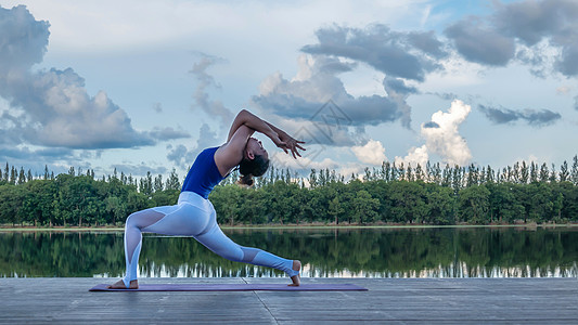 亚裔妇女练瑜伽姿势女性幸福平衡地面公园运动蓝色天空女孩反射图片