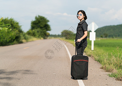 在公路上搭便车载行李的妇女农村成人旅游天空女性太阳镜假期冒险游客自由图片