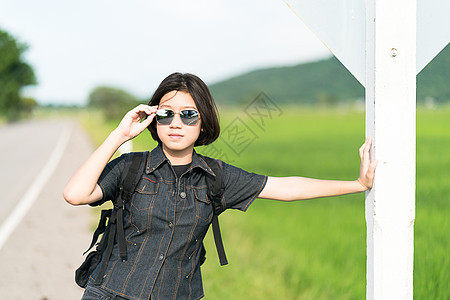 女人与背包搭便车在路上站在一起假期牛仔裤国家旅游游客短发自由天空女士女性图片