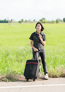 在公路上搭便车载行李的妇女短发女性农村女孩国家旅游场地天空自由游客图片