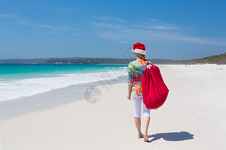 在澳洲的圣诞节     妇女与节日一起在海滩上散步高清图片