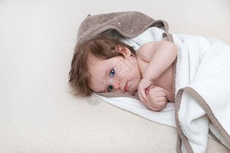 3个月大的婴儿在白色背景的毛巾上裹着毛巾 看着你图片
