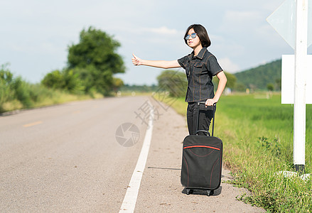 妇女短头发 行李搭便车和拇指举起场地牛仔裤游客女性短发冒险旅游远足女士太阳镜图片