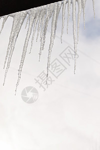 房子的雪顶上挂着危险的冰柱 巨大的冰柱城市高楼季节温度水晶天气天空阳光建筑冻结图片