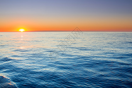 在开阔的海中静日出 天空平静明亮图片