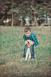 可爱帅气的蓝眼睛男孩在户外玩耍 带着令人惊叹的白色粉红色拉布拉多猎犬小狗 享受夏日阳光明媚的假期周末 充满快乐 快乐的微笑孩子和图片