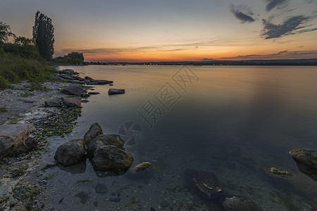 与湿岩石的海日落海景 平滑的波浪长时间曝光图片