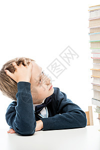 一个疲累男孩的肖像 在一张孤立的桌子上挂着一堆书图片