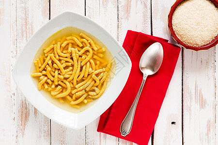 意大利薄汤的意大利皮卡图利黄色乡村食物木头桌子餐巾红色午餐盘子肉汤图片