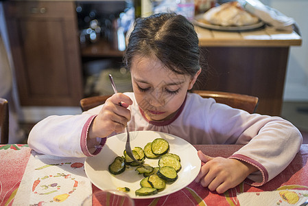 5岁女孩在厨房餐桌边吃煮熟的菜孩子们绿色午餐教育桌子孩子粉色食物睡衣营养图片