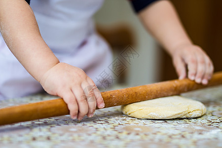 手用滚动针在桌子上烤面团 厨房里的小厨师烤面包糕点烹饪食物滚筒烘烤饼干木头小麦木板面包师图片