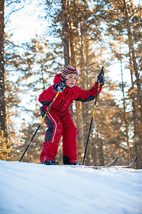 穿红衣服男孩穿红衣服的男孩在松树林里滑雪孩子滑雪者快乐活动微笑喜悦童年季节树木男生背景