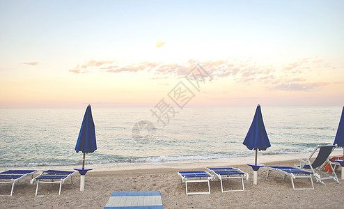 两只闭着的雨伞 和一些太阳床 在荒凉的海滩上图片