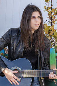 配有经典吉他女青年音乐家女士吉他手姿势黑色城市房子女孩青少年乐器图片