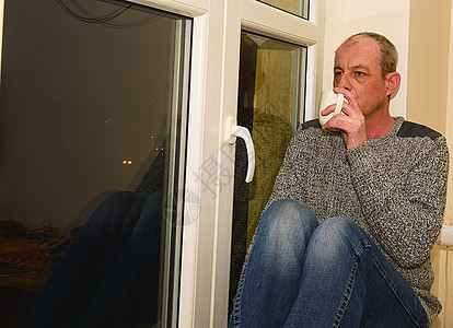 坐在窗户旁边的中年压抑男子 他喝着咖啡药品窗台疼痛男性孤独压力成人病人寂寞男人图片