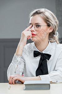 戴着时装眼镜的漂亮女孩坐在桌子上图片